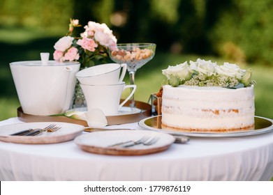 Table setting, teapot, teacups, cake, side view