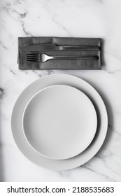 Table setting. Two grey plates with silver cutlery on the linen napkin. Minimalism style. High quality photo