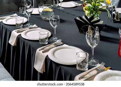 Table setting for a wedding or dinner event, black tablecloth white plates. - Powered by Shutterstock