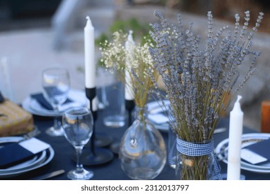 Table setting with white and blue dishes, candles and lavender flowers. Rustic Mediterranean style. Selective focus. - Powered by Shutterstock