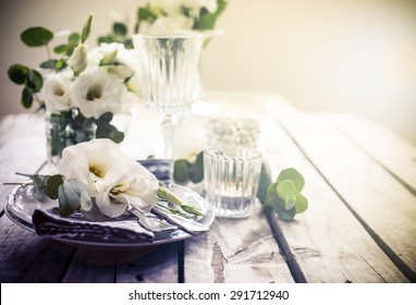 Table Setting With White Flowers, Candles And Glasses On Old Vintage Rustic Wooden Table. Vintage Summer Wedding Table Decoration.