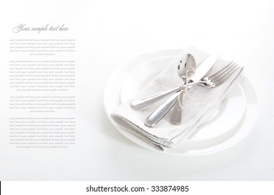 Table setting in white and gray colors with linen napkins and silverware