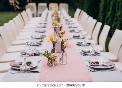 Table setting: white plate with two knives and two forks. There is a pink napkin on the plate. A restaurant. Holiday. Wedding. Decor