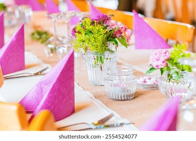 Table setup with pink napkins, floral centerpieces, and clear glassware creating a festive and elegant atmosphere suitable for celebrations, weddings, or social gatherings in a comfortable setting - Powered by Shutterstock