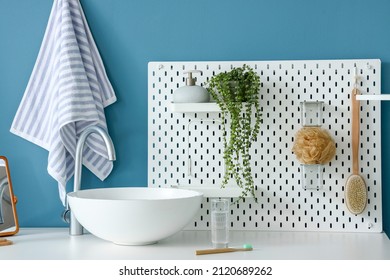 Table With Sink, Glass Of Water, Toothbrush And Pegboard Near Blue Wall