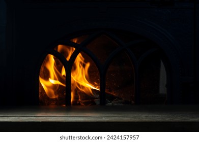 Table surface in front of firewood burning in the wooden stove. Cozy home atmosphere. Display for product.