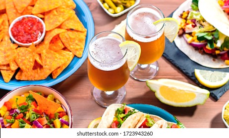 Table With Tacos, Mango Salsa, Nachos With Sauce, Guacamole, Lemon Beer. Appetizers And Traditional Mexican Dishes For Cinco De Mayo Or Taco Tuesday On Wooden Table Top, Copy Space