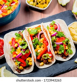 Table With Tacos, Mango Salsa, Nachos With Sauce, Guacamole, Lemon Beer. Appetizers And Traditional Mexican Dishes For Cinco De Mayo Or Taco Tuesday On Wooden Table Top, Copy Space