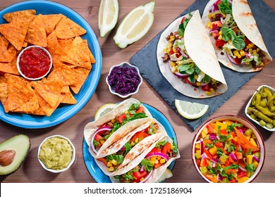 Table With Tacos, Mango Salsa, Nachos With Sauce, Guacamole, Lemon Beer. Appetizers And Traditional Mexican Dishes For Cinco De Mayo Or Taco Tuesday On Wooden Table Top, Copy Space