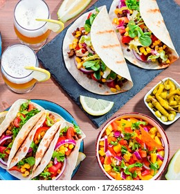 Table With Tacos, Mango Salsa, Nachos With Sauce, Guacamole, Lemon Beer. Appetizers And Traditional Mexican Dishes For Cinco De Mayo Or Taco Tuesday On Wooden Table Top, Copy Space