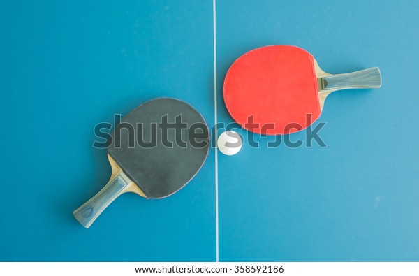 Table tennis bats and ball on a table with\
white vertical line. Concept of\
competition