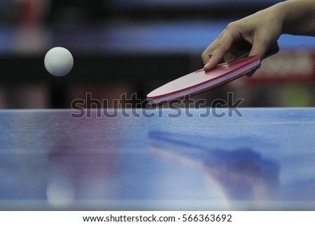 Table tennis ping pong paddles and white ball on blue board.
