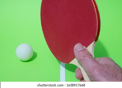 Table Tennis, Ping Pong Racket Held In Hand And Ball Resting Above The Gaming Table.