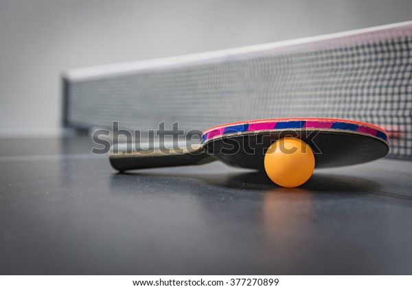 table\
tennis racket with orange ball on black\
table