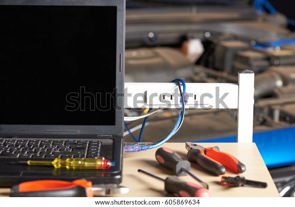 Table with tools for car computer diagnostic\
on blurred vehicle hood\
background.