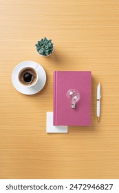 Table top objects - notebook and light blub on wooden tabke top. Conceptual ideation still life.