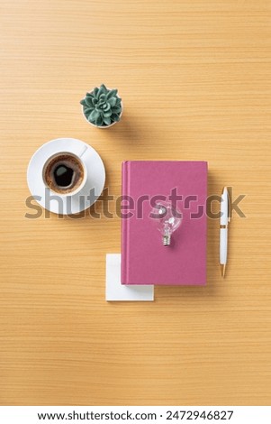 Table top objects - notebook and light blub on wooden tabke top. Conceptual ideation still life.