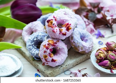 Table top scene of colorful doughnut cookies with edible flowers and birch sugar. Donut cookies. Pink and blue round raw cookies. Raw food, vegan menu. Black tulips. - Shutterstock ID 1687253365