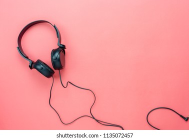 Table Top View Aerial Image Of Accessories Listening Radio Music Background Concept.Flat Lay Black Headphones On Modern Rustic Pink Paper Wallpaper.Free Space For Creative Design Text And Content.