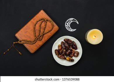 Table Top View Aerial Image Of Decoration Ramadan Kareem Holiday Background.Flat Lay Date With Rosary & Lighting.Essential Object Holy Koran Of Muslim On Modern Rustic Black Wooden At Office Desk.