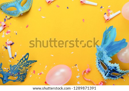 Table top view aerial image of beautiful colorful carnival festival background.Flat lay accessory object the mask & decor confetti and balloon on modern yellow paper at home office desk studio.