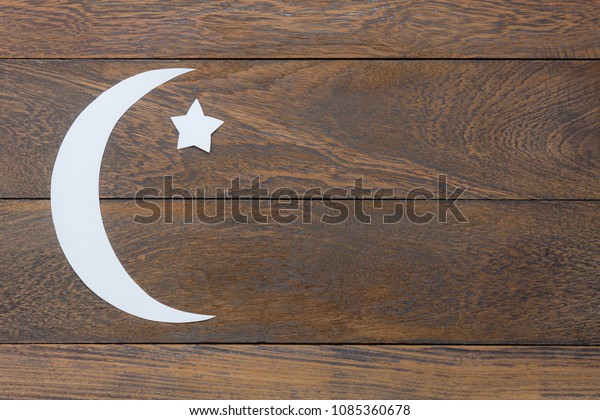 Table top view aerial image of decorations\
Ramadan Kareem holiday background.Flat lay DIY paper cut of white\
moon and star on modern rustic brown wooden plank at office desk\
and copy space backdrop.