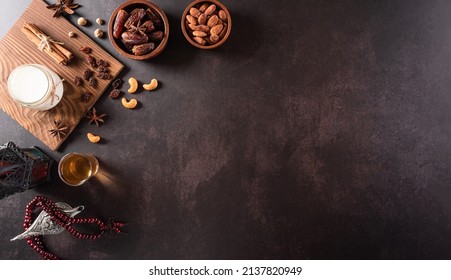 Table top view image of decoration Ramadan Kareem, dates fruit, aladdin lamp, milk and rosary beads on dark stone background. Flat lay with copy space. - Shutterstock ID 2137820949