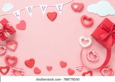 Table top view image of decoration valentine's day background concept.Flat lay arrangement of red shape & gift box with essential items on modern rustic pink paper with middle space for mock up design