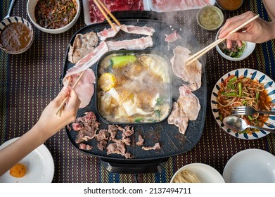 Table Top View Of People Enjoying Their Party By Korean BBQ And Shabu Shabu Dinner. Korean BBQ Is The Popular Method Of Grilling Meat Right At The Dining Table.