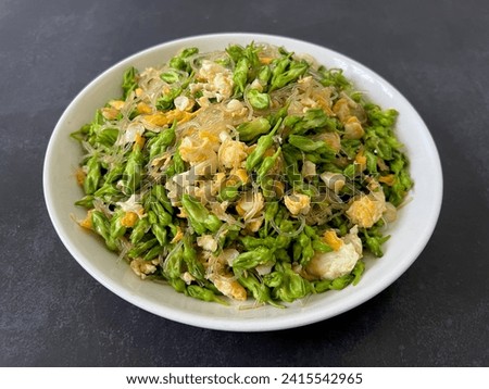 Table top view stir fried cowslip creepers with jelly noodles and eggs on black background.