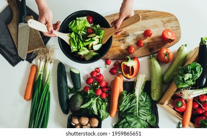 Table top view of woman hands making fresh salad in table full with organic vegetables. Directly above photo of housewife making lunch, mixing organic vegetables with mixing spoon at kitchen in home - Powered by Shutterstock