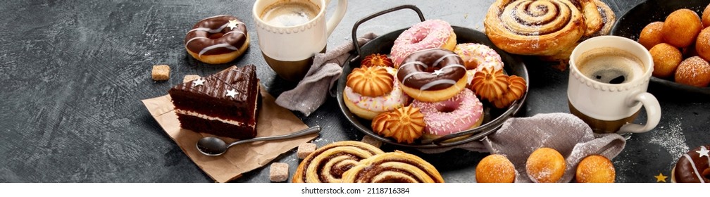 Table avec divers biscuits, beignets, gâteaux et tasses à café sur fond sombre. Panorama, bannière