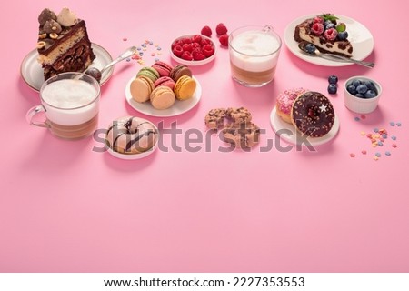 Table with various cookies, donuts, cakes, cheesecakes and coffee cups  on pink background.  Delicious dessert table. Copy space
