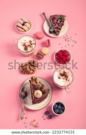 Table with various cookies, donuts, cakes, cheesecakes and coffee cups  on pink background.  Delicious dessert table. Top view, flat lay