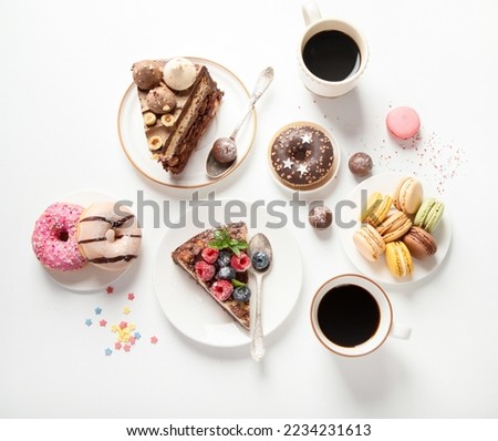 Table with various cookies, donuts, cakes, cheesecakes and coffee cups on white background.  Delicious dessert table. Top view, flat lay