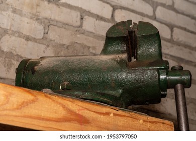 Table vise on a wooden base, against a background of a brick wall. Old green table vise covered with dust on a wooden base, against a background of a brick wall  - Powered by Shutterstock