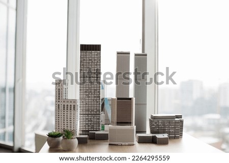 Table with white architectural scale cardboard model of building complex in empty modern architect office. Urban architecture development project for real estate property. [[stock_photo]] © 