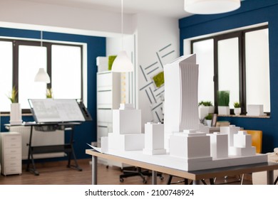 Table with white architectural scale foam model of building complex in empty modern architect office. Urban architecture development project for real estate property.
