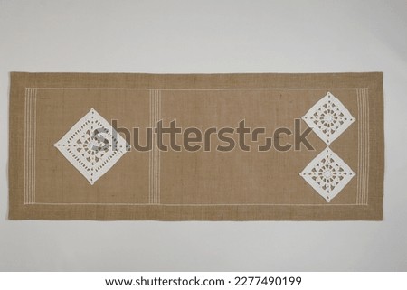 Tablecloth decorated with hand-embroidered motifs on colored cross-stitch