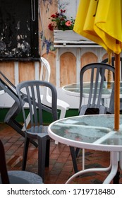 Tables And Chairs Stacked Together On Outdoor Patio Of An Empty Restaurant On Rainy Day