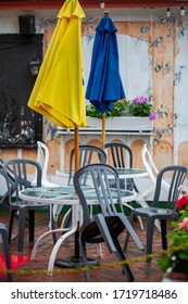 Tables And Chairs Stacked Together On Outdoor Patio Of An Empty Restaurant On Rainy Day