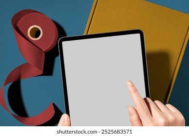 Tablet blank screen, packing parcel box, online shop business owner. Hand holding tablet. yellow box. packing product box. delivery box. tablet and parcel. hand holding tablet over parcel