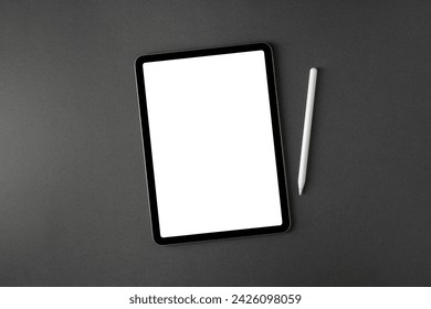 Tablet with blank screen and stylus on dark gray office desk