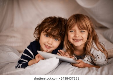 Tablet, blanket fort and portrait of kids relaxing, bonding and playing together at home. Happy, smile and young girl and boy children siblings laying in tent for fun sleepover in bedroom at house. - Powered by Shutterstock