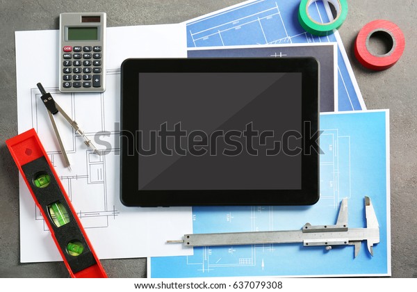 Tablet\
with blueprints and engineer equipment on\
table