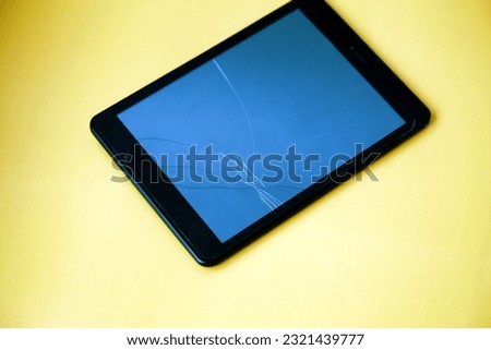 Tablet with broken screen on yellow background 