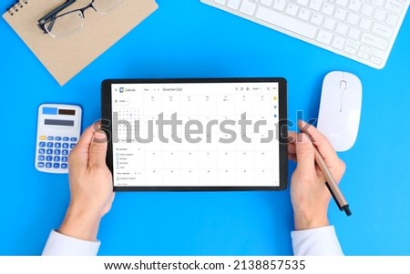 Tablet with calendar app on screen filled with different weekly appointments, meetings and tasks