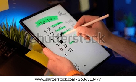 Tablet checklist digital notes productivity planning concept with hand writing and crossing out tasks using stylus in modern workspace
