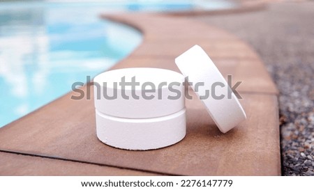 Tablet chlorine for swimming pool, white round chlorine on swimming pool background, chemical pool water maintenance
