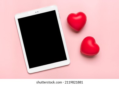 tablet for chooses gifts, makes purchase, two red hearts on pink table Top view Flat lay Holiday shopping list, Happy Valentine's day, party, online shop concept Mock up